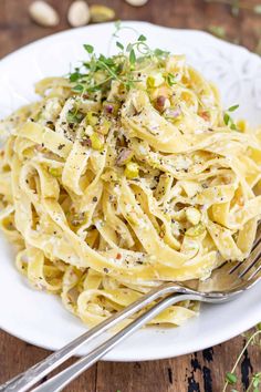 a white plate topped with pasta and garnished with parsley