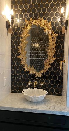 a bathroom sink with a mirror and lights on the wall above it, in front of a black tiled wall