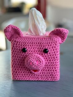 a pink tissue holder with a pig face on it's side, sitting on a table