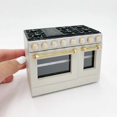 a miniature stove with two ovens on it's sides and a finger pointing at the door