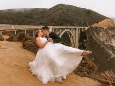 a bride and groom pose for a photo in front of the bixby bridge