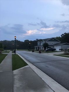 an empty street with houses in the background at dusk, as seen from across the street