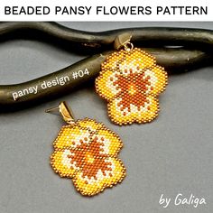 the beaded daisy flowers pattern is hanging from a pair of earrings on a branch