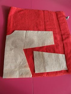 two pieces of red and white fabric on a pink surface