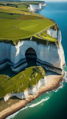 an aerial view of the white cliffs and green fields on the coast near the ocean