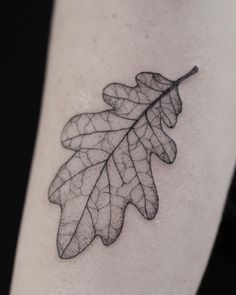 a single leaf tattoo on the right thigh, with black and white ink in it