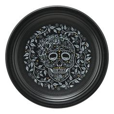 a black plate with a skull and leaves design on the side, in front of a white background