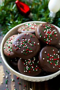 chocolate covered donuts in a white bowl with sprinkles and christmas decorations