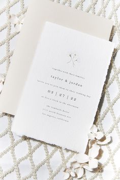 the wedding stationery is laid out on a white tablecloth with flowers and petals