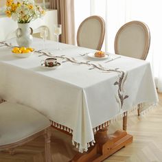 a dining table with two chairs and a vase filled with flowers