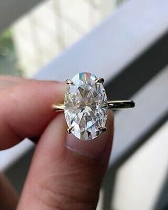 a close up of a person's hand holding a ring with a diamond in it