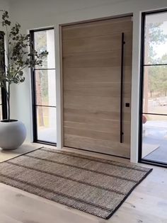 a large white vase sitting on top of a hard wood floor next to a wooden door