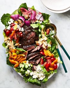 a salad with steak, tomatoes, lettuce and feta cheese