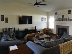 a living room filled with furniture and a flat screen tv mounted on the wall above a fire place