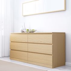 a white room with a wooden dresser and mirror