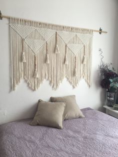 a bed with two pillows on it next to a wall hanging