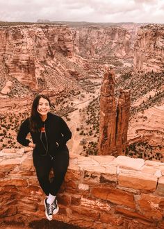 a woman sitting on the edge of a cliff with her headphones in her ears