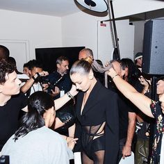 a group of people in a room with one woman getting her hair combed by another person