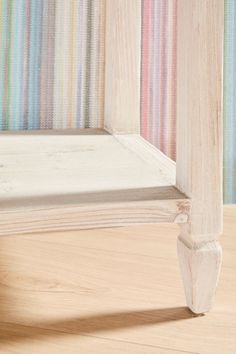 a close up of a bed frame on a wooden floor with multicolored wallpaper in the background