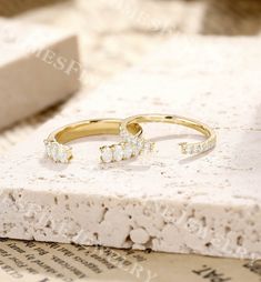 two gold rings sitting on top of a piece of white paper next to each other