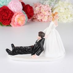 a figurine of a bride and groom laying on the ground next to flowers