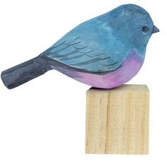 a blue bird sitting on top of a wooden block