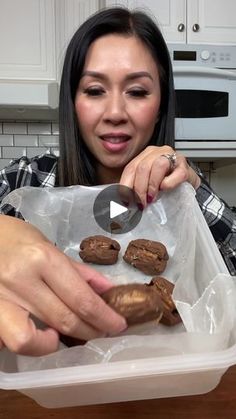 a woman holding a plastic container filled with cookies