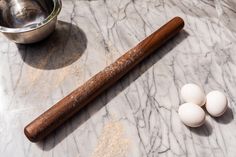 three eggs and a wooden spoon on a marble counter