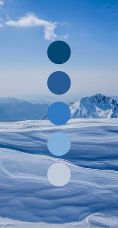 a blue and white photo with circles in the sky above snow covered ground, mountains behind