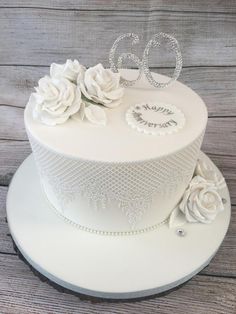 a white wedding cake with flowers and the number 50 on top is sitting on a wooden table