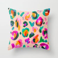 a pink pillow with colorful paint splattered on it's back and sides