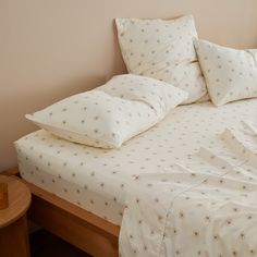 a bed with white sheets and pillows on top of it next to a night stand