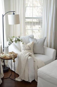 a living room with white furniture and pillows