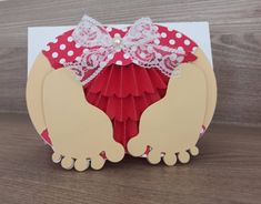 a card with two hands holding a red heart and white polka dot ribbon on it