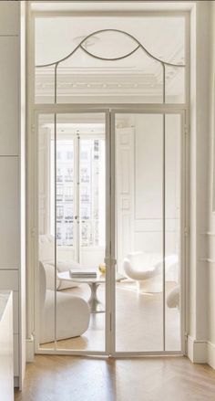 an open door leading to a living room with white furniture and walls in the background