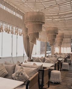 the restaurant is decorated with white linens and tasselled chandeliers hanging from the ceiling