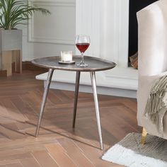 a glass of wine sitting on top of a table next to a chair and rug