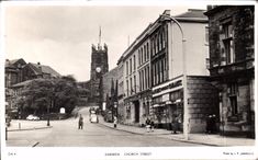 an old black and white photo of people walking down the street in front of buildings