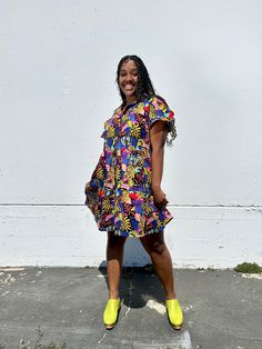 The Eloise is a sweet above-the-knee length dress. Made in our lightweight cotton poplin, this dress features a loose A-line silhouette with a collar, buttons all the way down the front, and has ruffled short sleeves and a tiered skirt that give it a fun whimsical vibe. 👩‍🎨 Featuring artwork by Neya Cotton Shirt Dress With Ruffles For A Day Out, Cotton Collared Shirt Dress With Ruffles, Collared Cotton Shirt Dress With Ruffles, Summer Cotton Shirt Dress With Ruffles, Casual Collared Dresses With Ruffles, Casual Collared Dress With Ruffles, Summer Ruffled Collared Dress, Summer Collared Ruffle Dresses, Summer Collared Dress With Ruffles