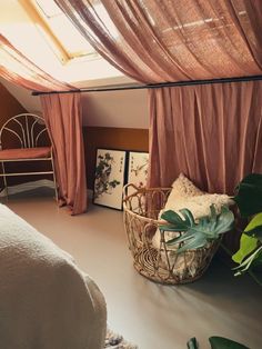 a bed sitting under a window next to a plant in a basket on the floor