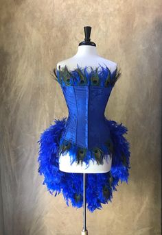 a blue corset with peacock feathers on it's bust and bottom, sitting on a mannequin