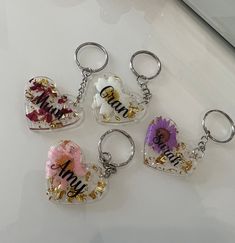 four heart shaped keychains with flowers and the word mom written on them are sitting on a white surface