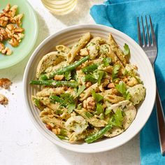 a white bowl filled with pasta and asparagus on top of a blue napkin