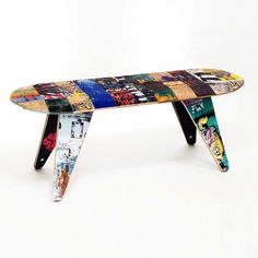 a multicolored skateboard shaped bench sitting on top of a white surface with graffiti all over it