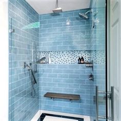 a bathroom with blue tiles on the walls and floor, along with a walk in shower