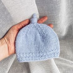 a hand is holding a blue knitted hat