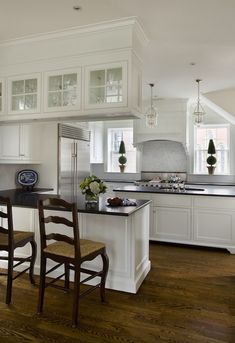 a large kitchen with white cabinets and wooden floors