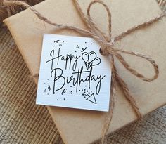 a gift wrapped in brown paper with the words happy birthday written on it next to some twine