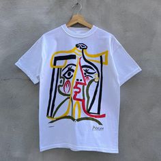 a white t - shirt with an abstract painting on it