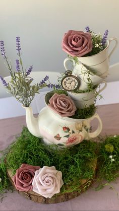 three teapots are stacked on top of each other with flowers and plants growing out of them